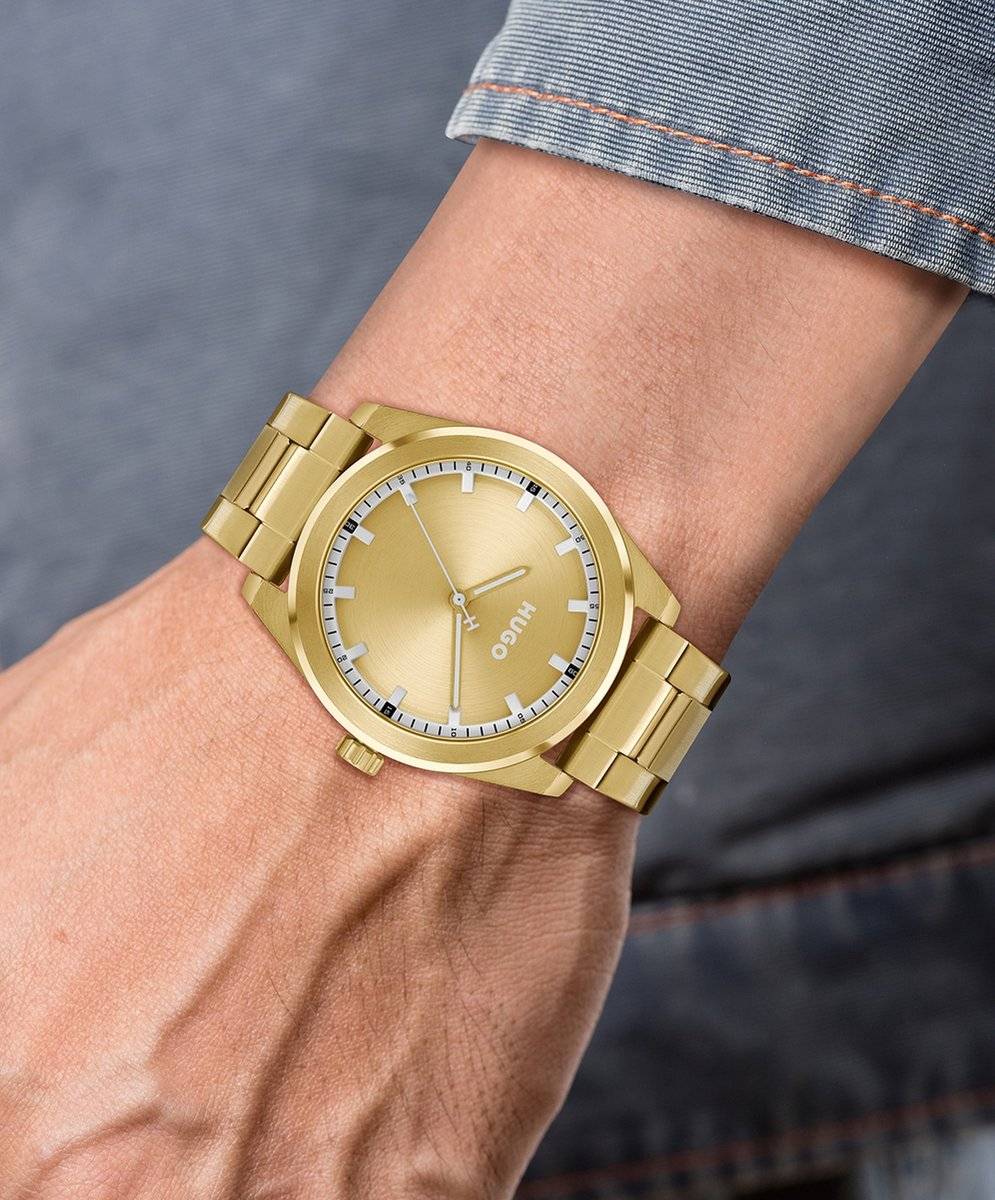 Hugo Boss Orange Bright HU1530354 Herenhorloge 42mm met goudkleurige kast en band, gedragen om pols. Stijlvol accessoire voor herenmode.