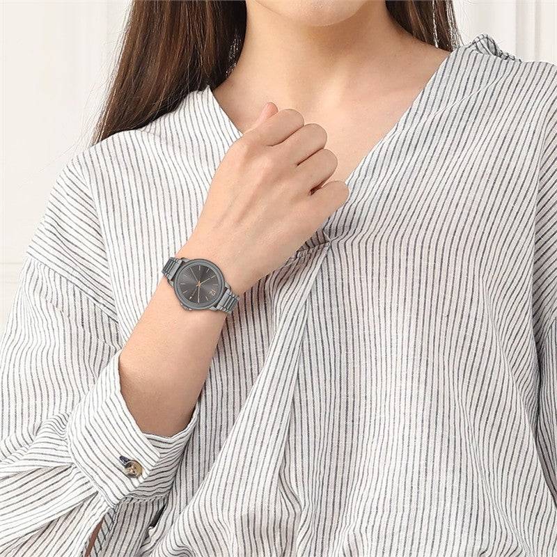 Lacoste horloge dames - LC2001220 met grijze wijzerplaat en metalen band, gedragen door vrouw in gestreepte blouse. Elegant dameshorloge van 38mm.