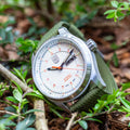 Luminox xl 1907 nf Atacama Field Automatic Herenhorloge 45mm met witte wijzerplaat en groene nylon band, outdoor gepresenteerd tussen bladeren.
